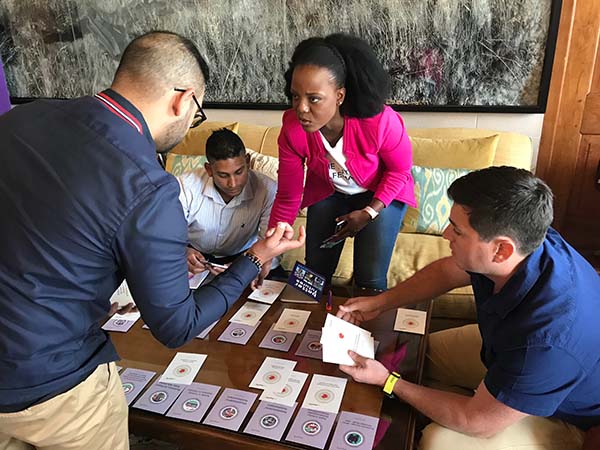 Four Insurance Apprentice participants surround the table while staring eye-to-eye.