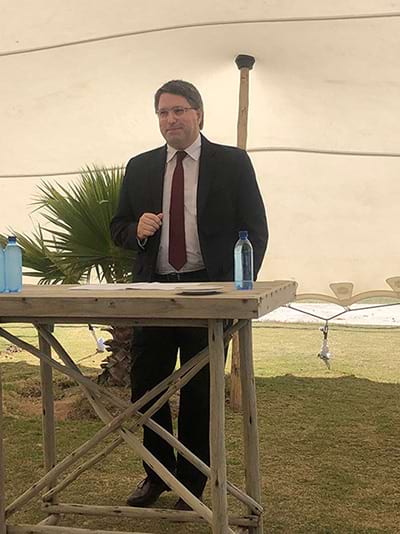 Quinton Roos of Trucklogix wearing a suit standing at a table